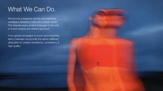 A person stands against a blurred blue background, captured in soft focus. The individual wears an orange-red top, and their face appears slightly obscured. The overall atmosphere is serene and artistic, with a dreamy quality created by the motion and color contrast, combining the dynamic figure with the calmness of the surrounding hues.