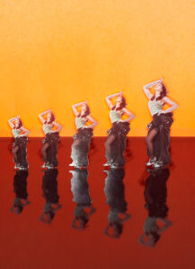 Five identical cutouts of a woman striking a pose are arranged in a row. They stand on a glossy red surface, creating clear reflections beneath them. The background features a warm, bright orange color, adding contrast to the figures. Each cutout gradually increases in size from left to right, creating a sense of perspective and progression.
