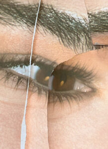 A close-up of an eye, showcasing dark lashes and a well-defined eyebrow. The skin has a natural complexion, and there are noticeable torn or folded paper effects, creating an abstract, layered look. The overlapping elements give the scene a fragmented and textured appearance, with light reflections adding depth to the eye's surface.