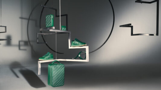 A minimalist arrangement showcases green sneakers and bags on suspended geometrical platforms, creating a modern, artistic display. Shadows and lighting add depth, emphasizing the sleek, contemporary aesthetic. The scene is set against a neutral background with circular elements, highlighting the contrast between the vibrant green items and the monochrome setting, resulting in a stylish, avant-garde composition.