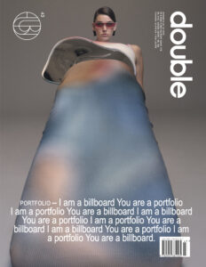 A person, wearing sunglasses, stands confidently while dressed in a distinctive, avant-garde outfit. The attire features a dynamic blend of colors, creating a modern and artistic appearance. The perspective is low, emphasizing the unique style of the clothing. The overall vibe is contemporary and fashion-forward, capturing a bold and creative aesthetic without revealing any textual elements.