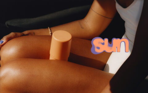 The scene focuses on a person lounging in the sun, wearing a white outfit. A golden-brown skin tone complements a sunlit glow. A sunblock stick with a pastel orange hue rests on their leg. Shadows and light interplay to highlight the subject's relaxed demeanor, while minimal accessories, like a bracelet and nail polish, add subtle detail.