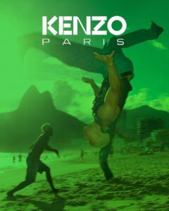 A vibrant scene depicts a person performing an acrobatic flip on a sandy beach under a greenish sky. In the background, figures are silhouetted against two large mountains and towering buildings. The atmosphere is dynamic, suggesting a lively, urban beach environment with a sense of energy and movement amidst natural and architectural elements.