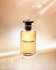 A sleek glass bottle filled with amber liquid stands elegantly against a softly glowing background of peach and gold hues. Light reflects gently off its smooth surface, highlighting the simple, modern design. The round, dark cap adds a contrasting touch, creating a sense of luxury and sophistication. The overall ambiance evokes warmth and elegance.