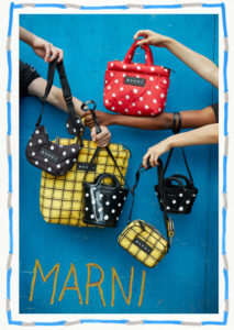 A vibrant display features hands holding a variety of stylish bags against a blue backdrop. The bags come in polka dot and checkered patterns, showcasing colors like red, black, and yellow. Each hand elegantly presents a different design, emphasizing a playful and fashionable theme. The overall composition highlights creativity in modern accessory design.