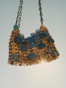 A stylish handbag is crafted from interlinked metallic elements, showcasing a variety of intricate patterns and motifs. Its design features a series of circular and rectangular gold-toned links, giving it a sophisticated and modern appearance. The chain strap consists of matching links, adding to its cohesive look. This accessory is well-lit and set against a soft, neutral backdrop.