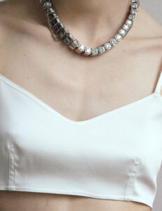 A group of young people sit together in a cozy indoor setting with wooden paneling. They engage in conversation and laughter, creating a relaxed and friendly atmosphere. Several glasses and bottles suggest a social gathering. The environment is warm and inviting, with a subtle mix of modern and rustic elements, including a foosball table in the background.