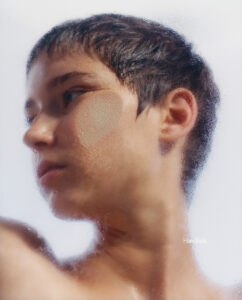 A profile of a person with short hair, gazing thoughtfully to the side. The background is smooth and blurred, emphasizing the calm expression and serene mood. Their skin appears soft, with light tones and gentle lighting casting subtle shadows. The composition focuses on simplicity and tranquility, highlighting the beauty in minimalism and introspection.