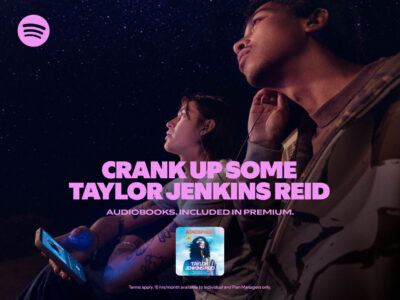 Two people are gazing upwards, immersed in their own worlds, under a starry night sky. One holds a phone with earphones connected, enveloped in a serene atmosphere. Both display an expression of introspection, capturing a moment of calm. Their attire is casual, suggesting a relaxed, intimate setting, perfect for listening to something captivating.