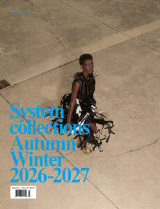 A person walks on a large, cracked concrete surface. They wear a unique, flowing black and white garment, with multiple ribbon-like elements. Their direct gaze exudes confidence. The footwear is vibrant, providing a pop of color. The overall atmosphere combines urban and artistic elements, highlighting a blend of modern fashion with a stark, minimalist backdrop.