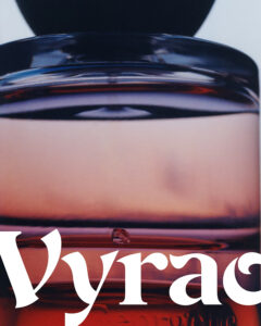 A glass container features a gradient of deep purple to light pink hues, with a sleek, rounded cap at the top. The reflective surface captures ambient light, emphasizing the rich, liquid contents within. The composition highlights elegance and allure, combining a modern design with a sense of luxury and sophistication.
